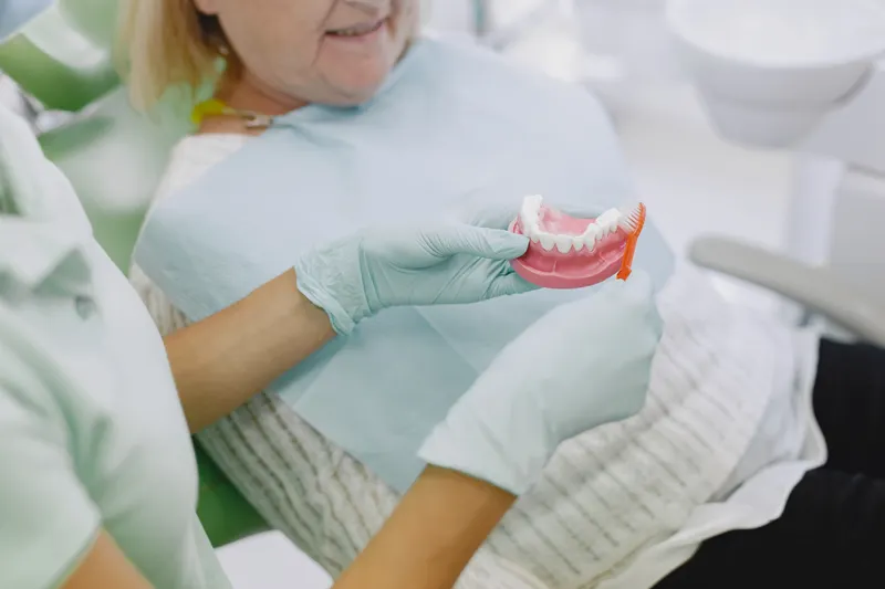 A dentist shows a set of false teeth to an older patient
